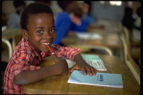 ANGOLA: A UNICEF-supplied notebook on his desk, eight-year-old Bruno Marques, a war orphan, smiles, sitting in class at the UNICEF-assisted Lar de Infancia Otchio primary school in the south-western town of Lubango, where he also lives. Continuing for more than two decades, the civil war in Angola has contributed to the death of some 500,000 children, as well as created 70,000 amputees including 8,000 children under the age of five. The country's infrastructure has been largely destroyed, including 25 per cent of its schools and clinics, and 75 per cent of small-town and rural water supplies. With some 12 million landmines, Angola is Africa's most heavily mined country, claiming 150-200 victims a week. In addition to programmes in primary health care, nutrition, water and sanitation, and agricultural rehabilitation, UNICEF supports landmine awareness campaigns, the demobilization of soldiers, especially child soldiers, as well as special camps for war-orphaned children and displaced people made destitute by the war.