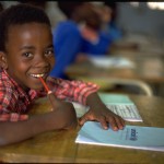 ANGOLA – Giacomo Pirozzi/ UNICEF-supplied notebook on his desk, eight-year-old Bruno Marques, a war orphan, smiles, sitting in class at the UNICEF-assisted Lar de Infancia Otchio primary school in the south-western town of Lubango.