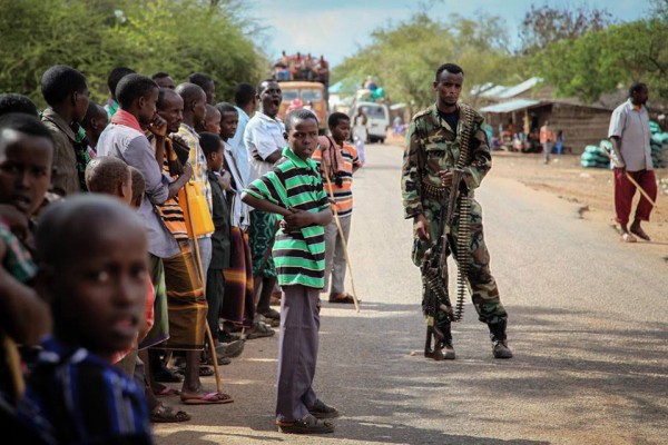 Residents of the village of Modmoday, 40 kilometres east of the town of Baidoa, Somalia, look on as a soldier of the Somali National Army (SNA) keeps guard. Photo: AU-UN/IST