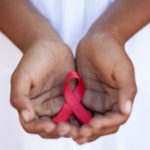 Child’s hands holding an HIV awareness ribbon, Cape Town, South Africa – Big Five Images via Getty Images
